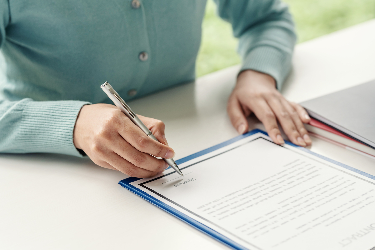 Close-up of a woman hand holding a pen about to sign contract do